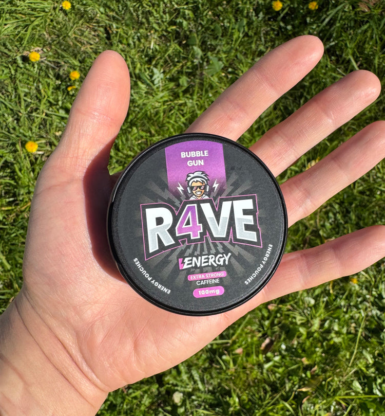 Hand holding a container of R4VE energy drink mix against a grassy background