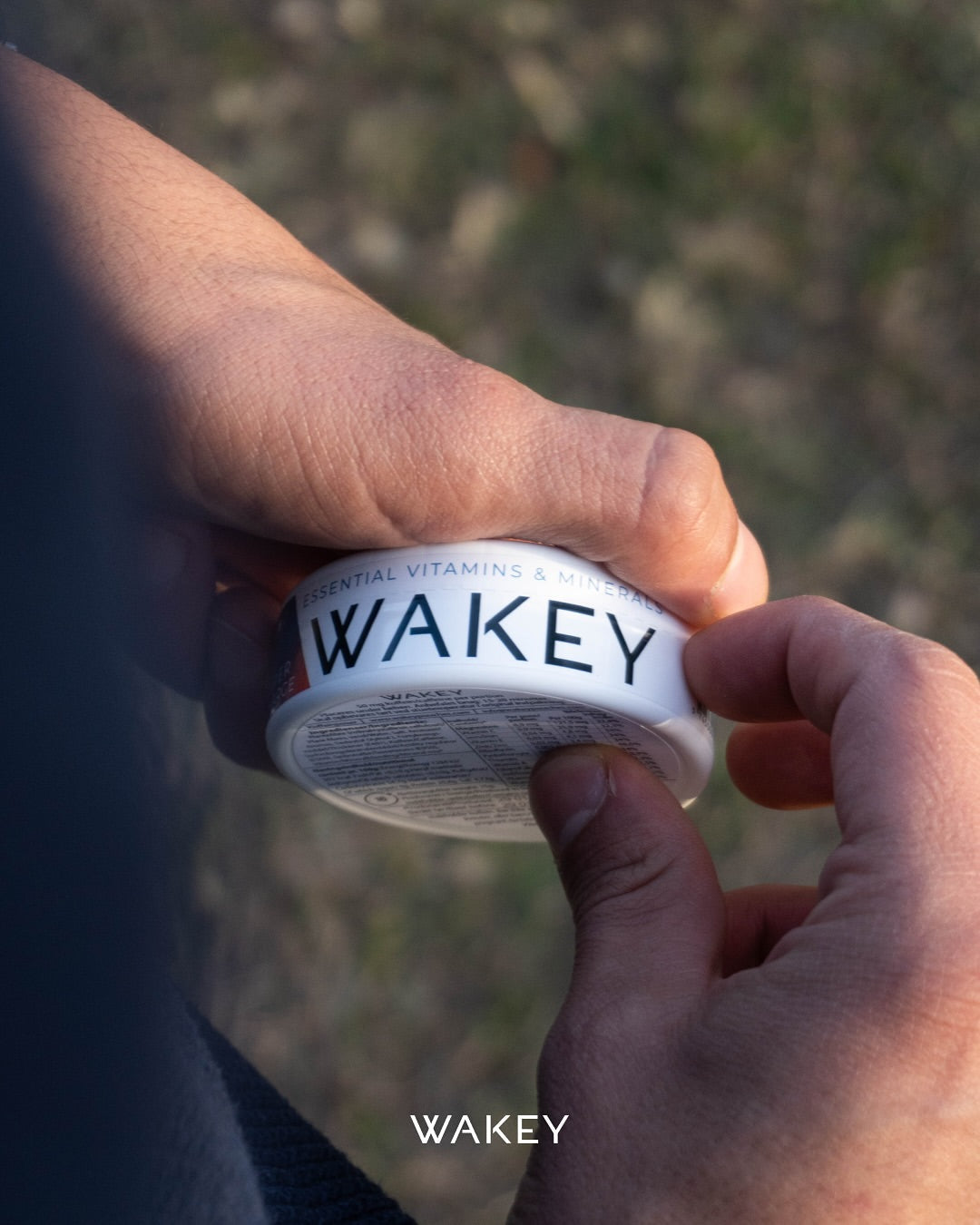 A person holding a can of WAKEY showcasing the rim of the can 'Essential vitamins and minerals, WAKEY'
